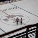 A pair of linesmen standing in the middle of the ice during a hockey game.