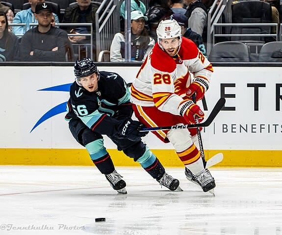 Elias Lindholm passing the puck under pressure during an NHL hockey game against the Seattle Kraken